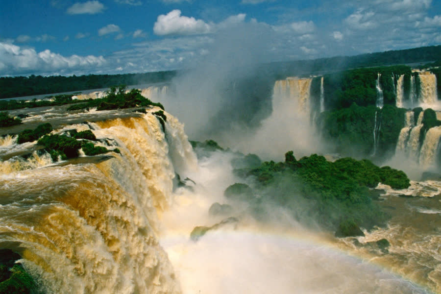 Cataratas do Iguaçu cercadas por floresta tropical, com névoa e arco-íris